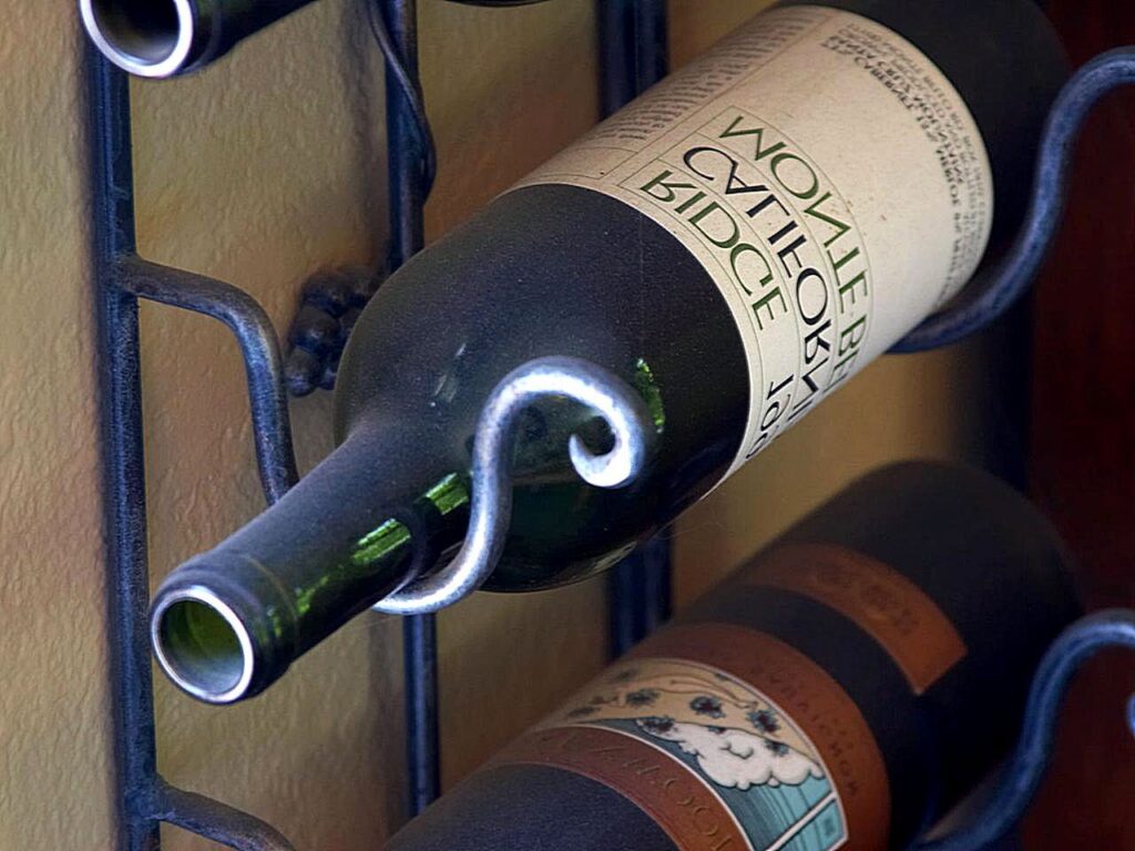 Close view of labeled wine bottles resting horizontally in a metal rack